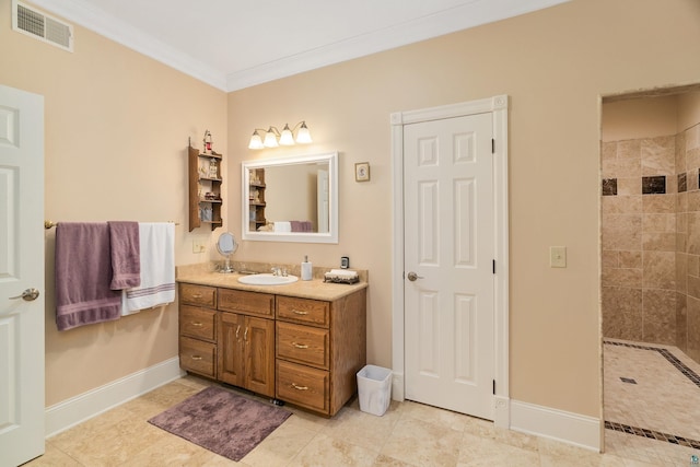 full bathroom featuring vanity, visible vents, baseboards, ornamental molding, and tiled shower