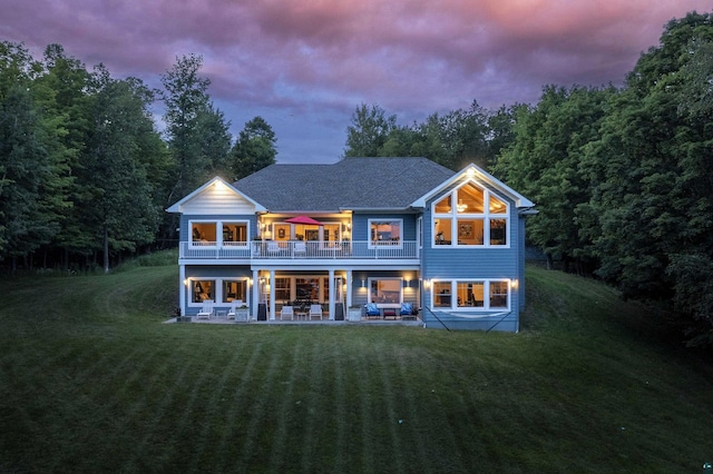 back of property with a patio area, an outdoor hangout area, a lawn, and roof with shingles