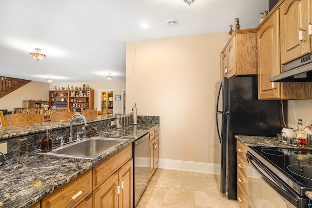 kitchen featuring a sink, dark stone counters, dishwasher, under cabinet range hood, and baseboards