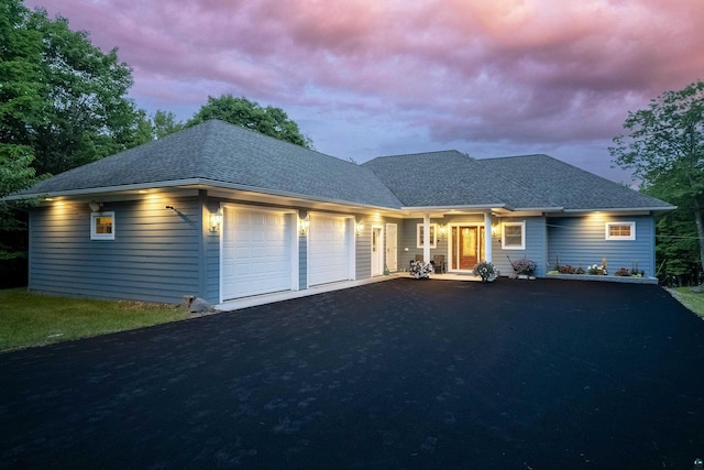 ranch-style house with aphalt driveway, roof with shingles, and a garage