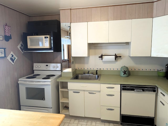 kitchen with sink, wood walls, white cabinetry, and white appliances