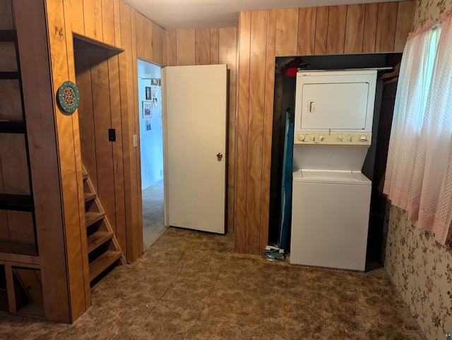 laundry area featuring carpet flooring, stacked washer and dryer, and wooden walls