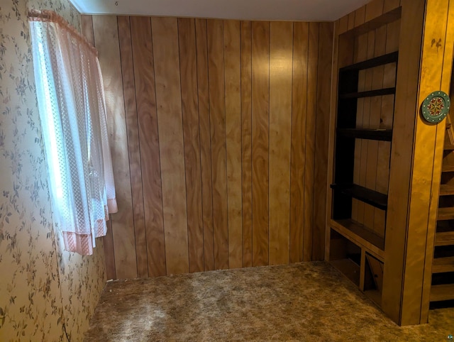 carpeted empty room with wood walls