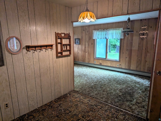 carpeted spare room featuring wood walls and a baseboard heating unit