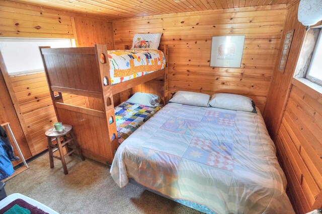 bedroom featuring wooden walls, wooden ceiling, and carpet flooring