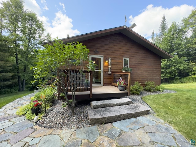 back of house featuring a lawn and a wooden deck