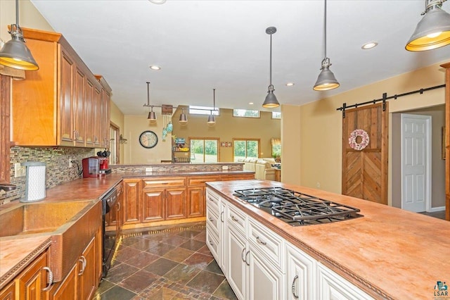 kitchen featuring tasteful backsplash, dark tile patterned floors, a barn door, dishwasher, and stainless steel gas cooktop