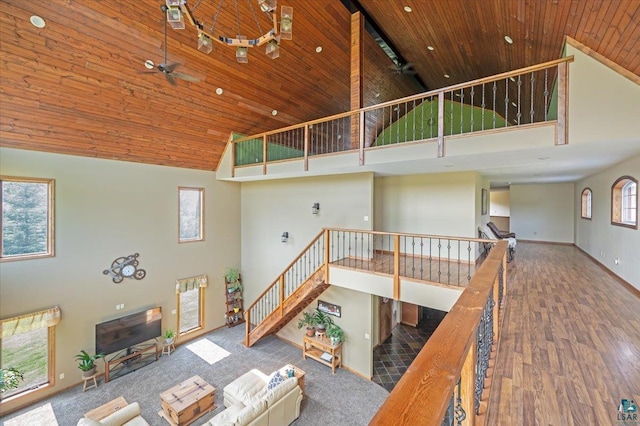 unfurnished living room featuring a wealth of natural light, wooden ceiling, ceiling fan, and high vaulted ceiling