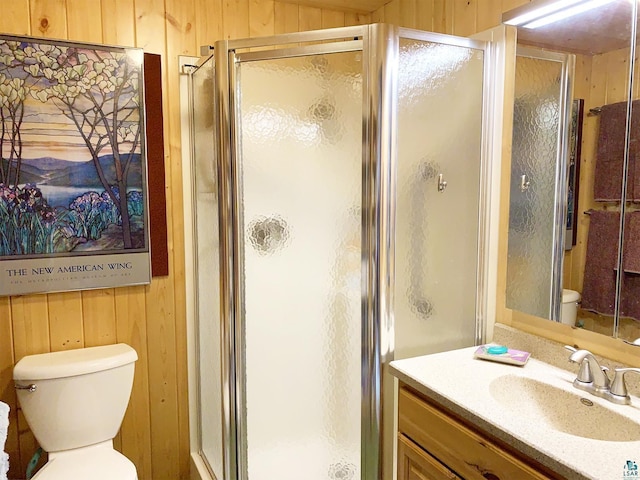 bathroom with wood walls, toilet, and a shower with shower door