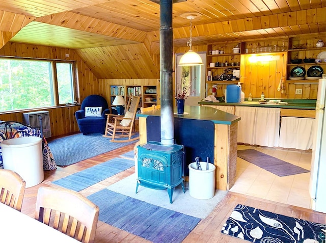 living room featuring built in features, a wood stove, wooden walls, wooden ceiling, and lofted ceiling