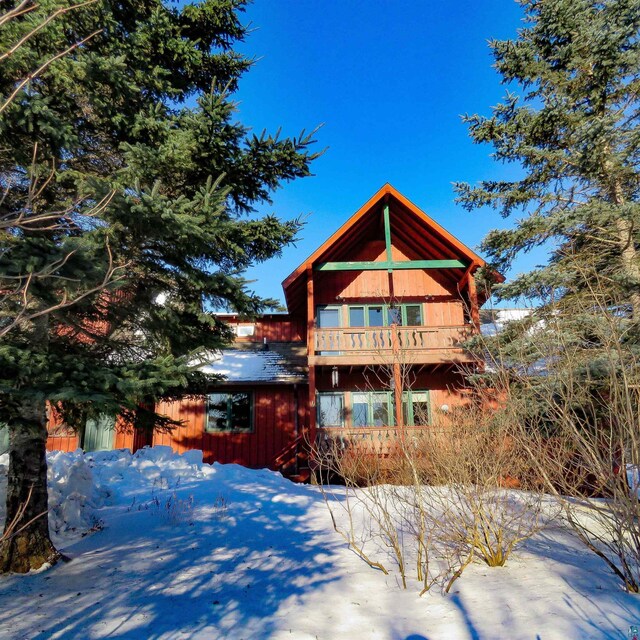 back of property with a balcony, a patio area, and a lawn