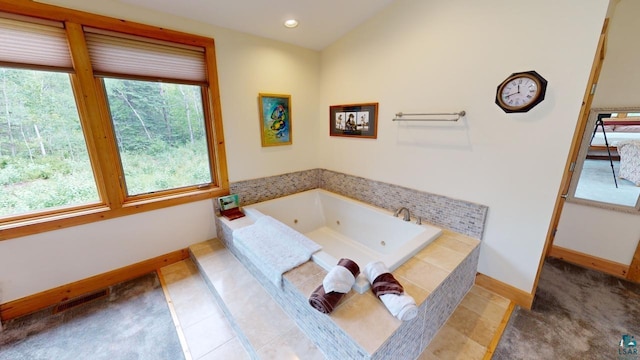 bathroom featuring tile patterned flooring, vaulted ceiling, and a relaxing tiled tub