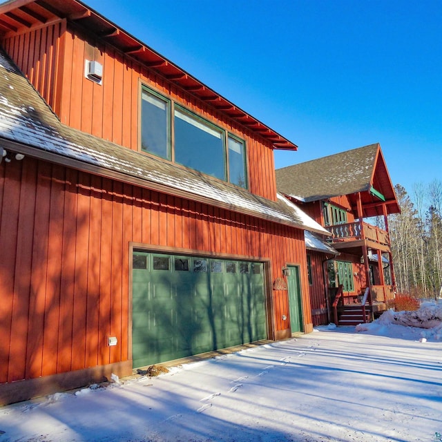 view of snowy exterior featuring a balcony and a garage