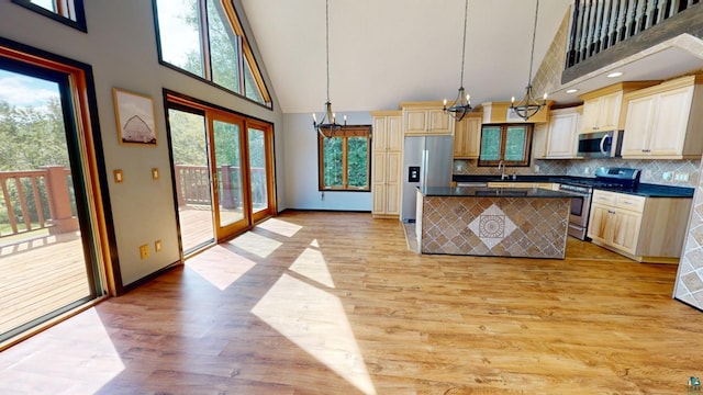 kitchen featuring dark countertops, pendant lighting, a chandelier, stainless steel appliances, and backsplash