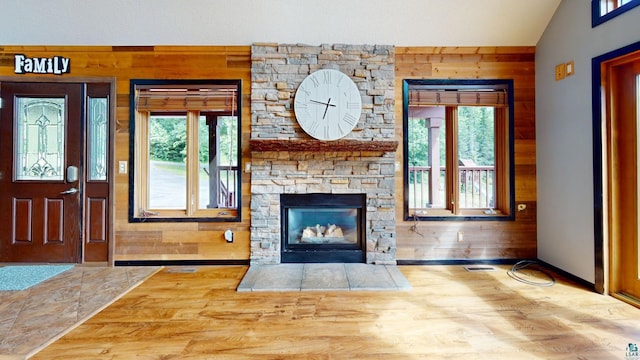 unfurnished living room with wood finished floors, wood walls, plenty of natural light, and a fireplace