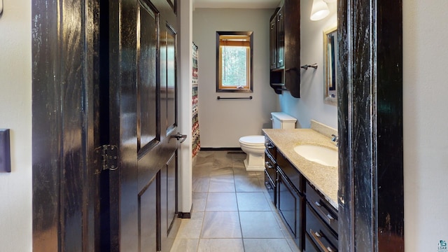 bathroom with baseboards, vanity, toilet, and tile patterned floors