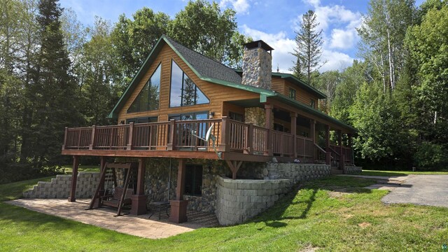 back of house featuring a wooden deck, a patio area, and a lawn