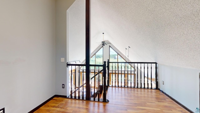 bonus room with baseboards, a ceiling fan, lofted ceiling, wood finished floors, and a textured ceiling