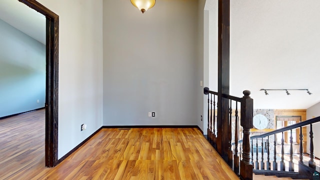 interior space with light wood-type flooring, rail lighting, and baseboards