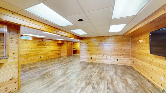 spare room featuring a paneled ceiling, wood finished floors, and wood walls