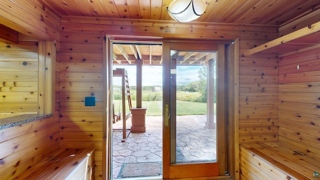 doorway with wood ceiling and wooden walls