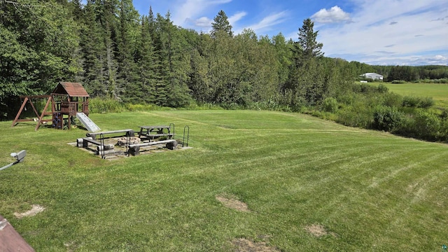 view of yard featuring a playground and a wooded view