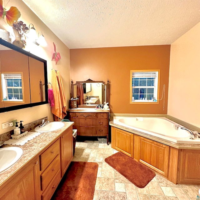 bathroom featuring a textured ceiling, a tub to relax in, dual bowl vanity, and tile patterned floors