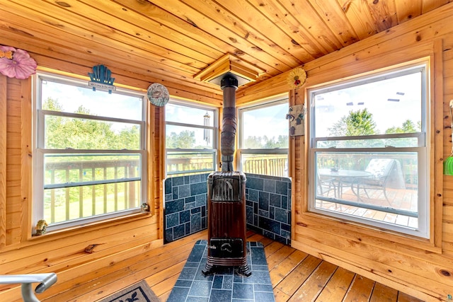 sunroom with wooden ceiling, a healthy amount of sunlight, and a wood stove