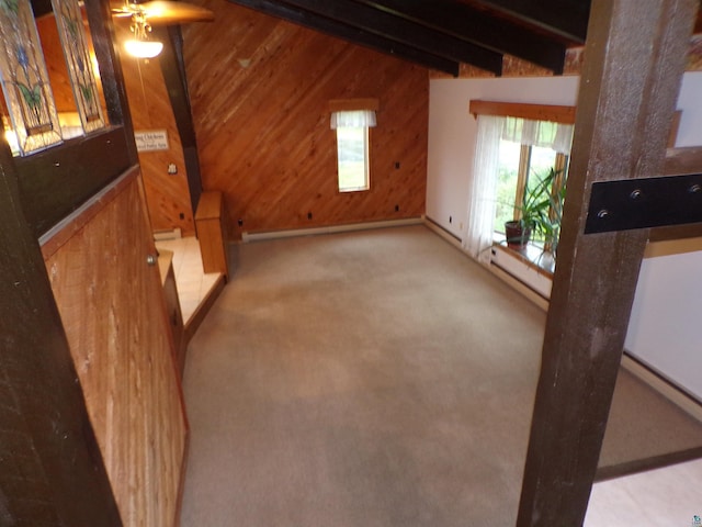 unfurnished living room featuring wood walls, lofted ceiling with beams, and light colored carpet