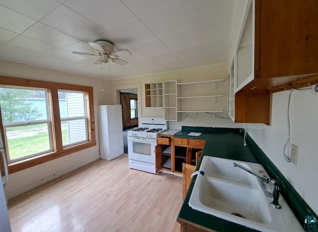 kitchen featuring white range with gas stovetop, ceiling fan, light wood-style floors, open shelves, and a sink