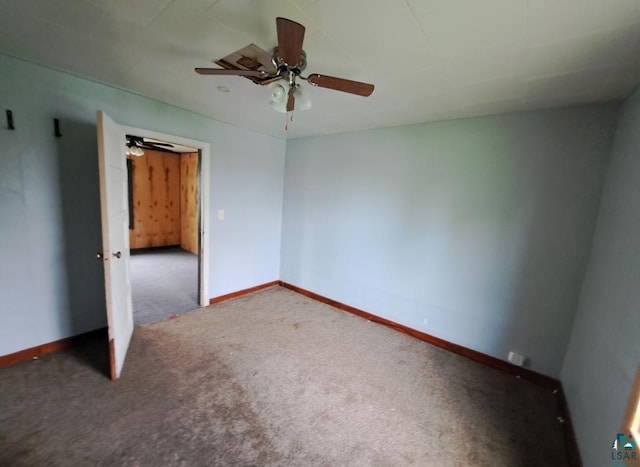 unfurnished bedroom with a ceiling fan, dark carpet, and baseboards