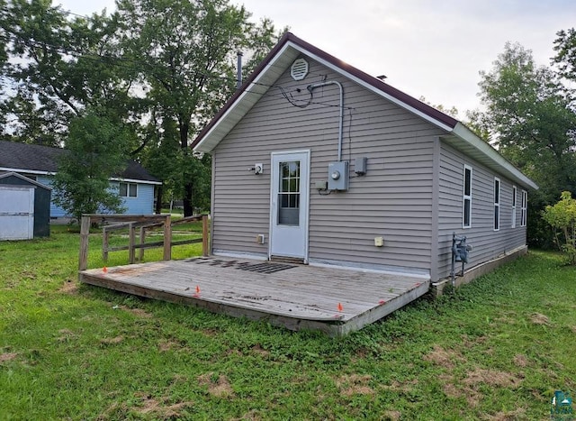 back of property with a wooden deck and a yard