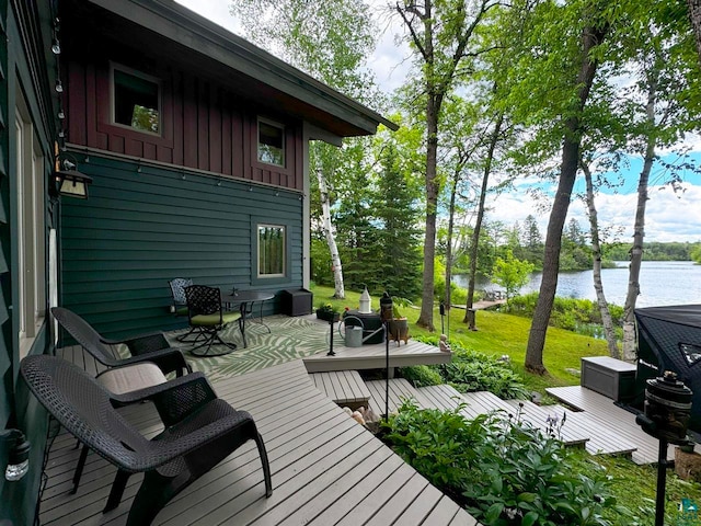 deck featuring an outdoor living space, a water view, and a yard