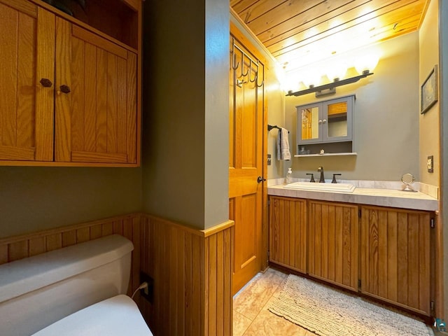 half bathroom featuring toilet, wood ceiling, wainscoting, wooden walls, and vanity