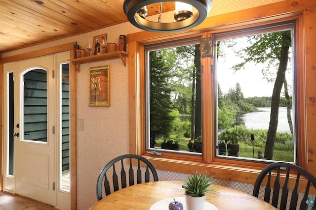 dining area featuring a water view, wood ceiling, and wallpapered walls