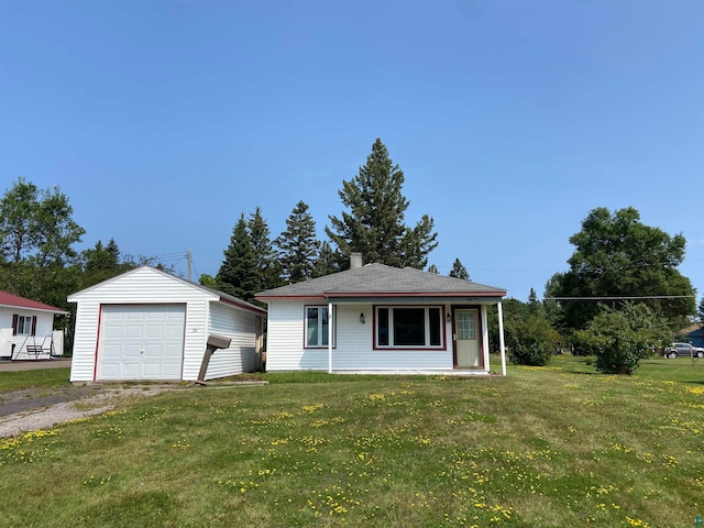 view of front of home featuring a front lawn, a garage, and an outbuilding