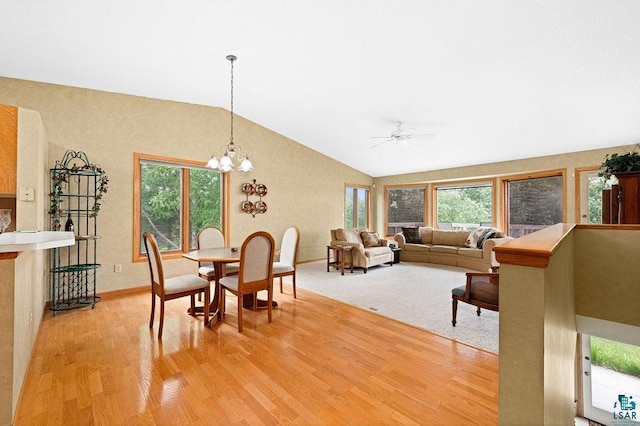 dining space featuring baseboards, vaulted ceiling, wood finished floors, and ceiling fan with notable chandelier