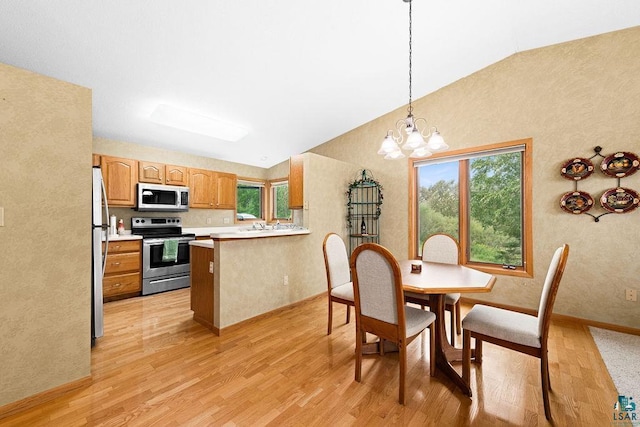 kitchen with a peninsula, light countertops, appliances with stainless steel finishes, hanging light fixtures, and light wood finished floors