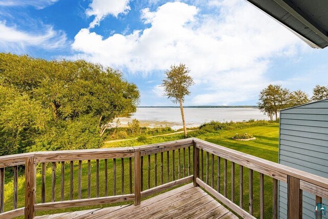 wooden terrace with a yard and a water view