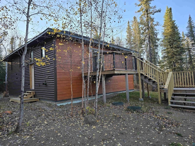 view of property exterior with faux log siding, stairway, and a wooden deck