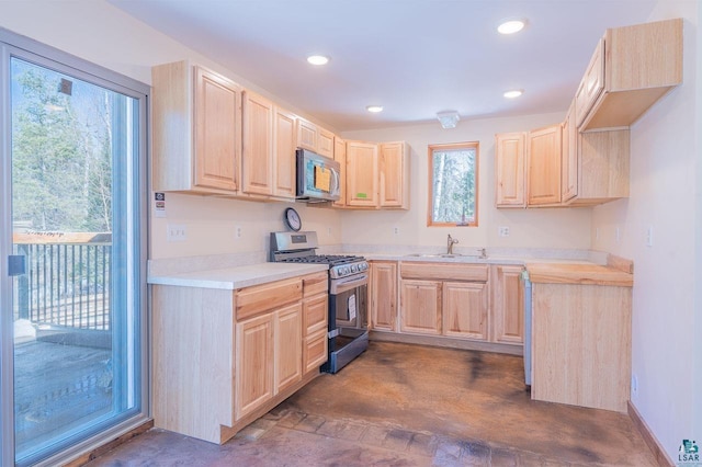 kitchen with light brown cabinetry, appliances with stainless steel finishes, light countertops, and a sink