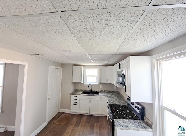 kitchen featuring dark hardwood / wood-style floors, stainless steel appliances, sink, white cabinetry, and a drop ceiling