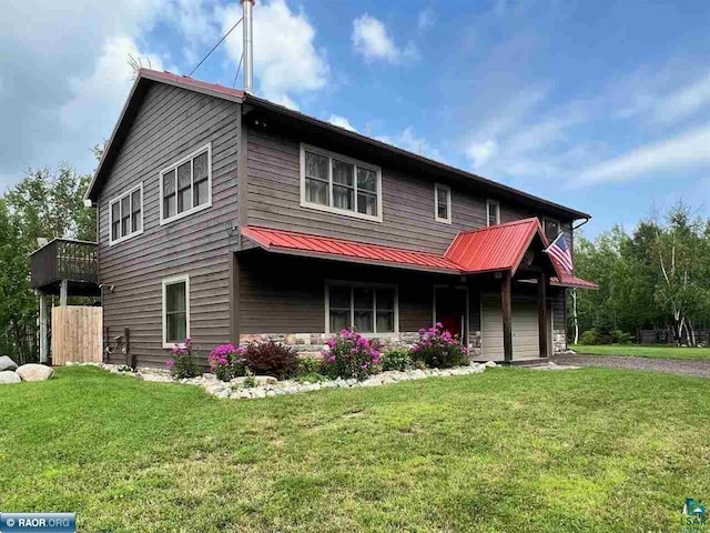 view of front of house with metal roof, driveway, and a front lawn