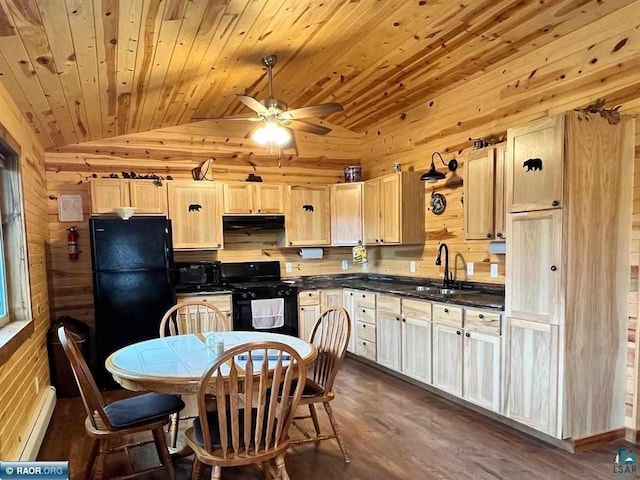 kitchen featuring lofted ceiling, dark countertops, a sink, under cabinet range hood, and black appliances