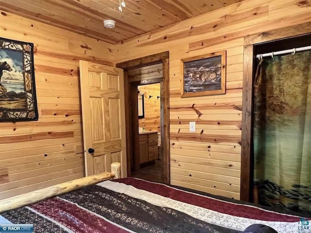 bedroom featuring wood ceiling, wooden walls, and ensuite bath