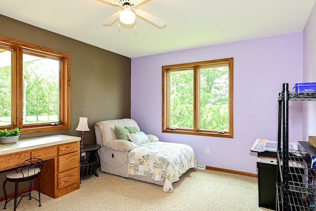 bedroom with light colored carpet, ceiling fan, and multiple windows