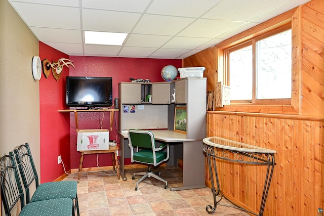 office featuring a paneled ceiling and wood walls