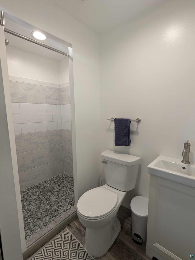 bathroom with vanity, toilet, hardwood / wood-style floors, and a tile shower