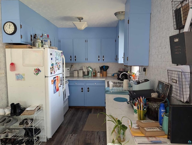 kitchen with blue cabinets, white fridge, sink, and dark hardwood / wood-style flooring