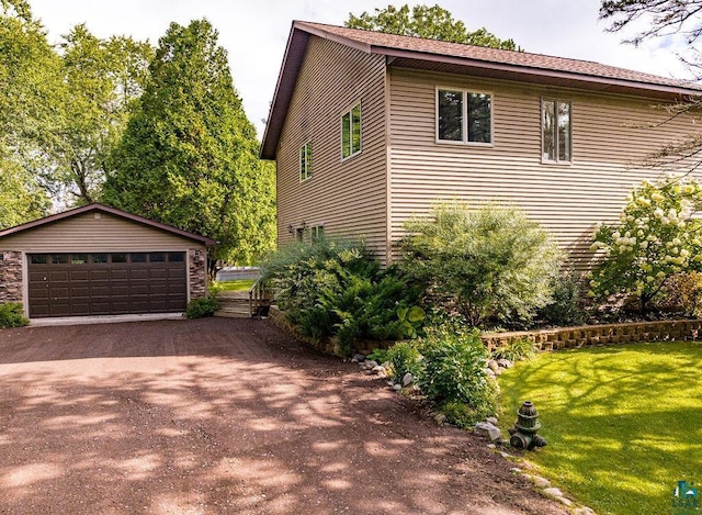 view of property exterior with a lawn, a garage, and an outbuilding